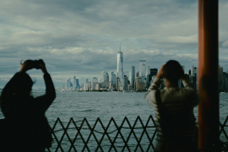 Two people photograph skyline from a boat.